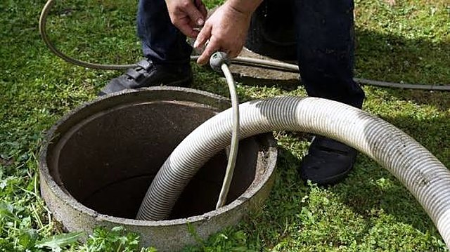 Technician cleaning septic tank access hatch