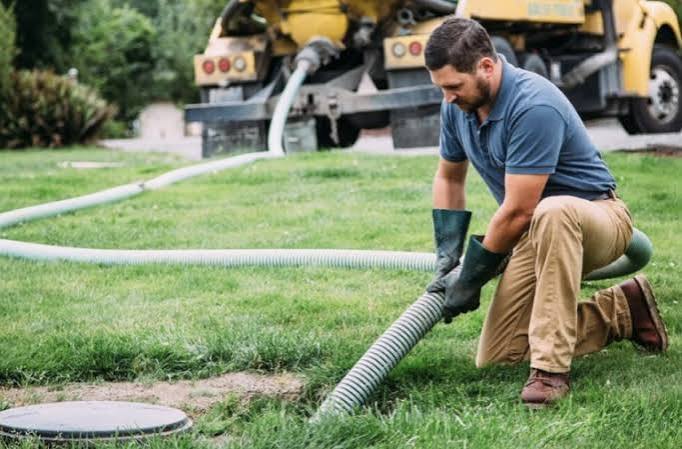 Worker cleaning septic tank with vacuum truck
