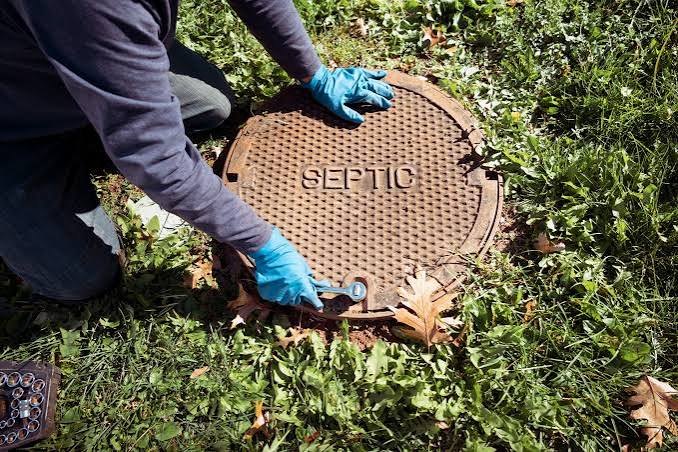 Technician opening septic tank access cover